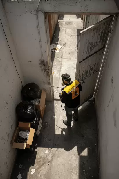 Especialista de Fumimaster fumigando un pasillo abierto con bolsas de basura para eliminar plagas.