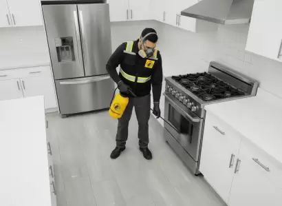 Especialista de Fumimaster fumigando en cocina blanca, utilizando productos que no manchan pisos ni superficies.